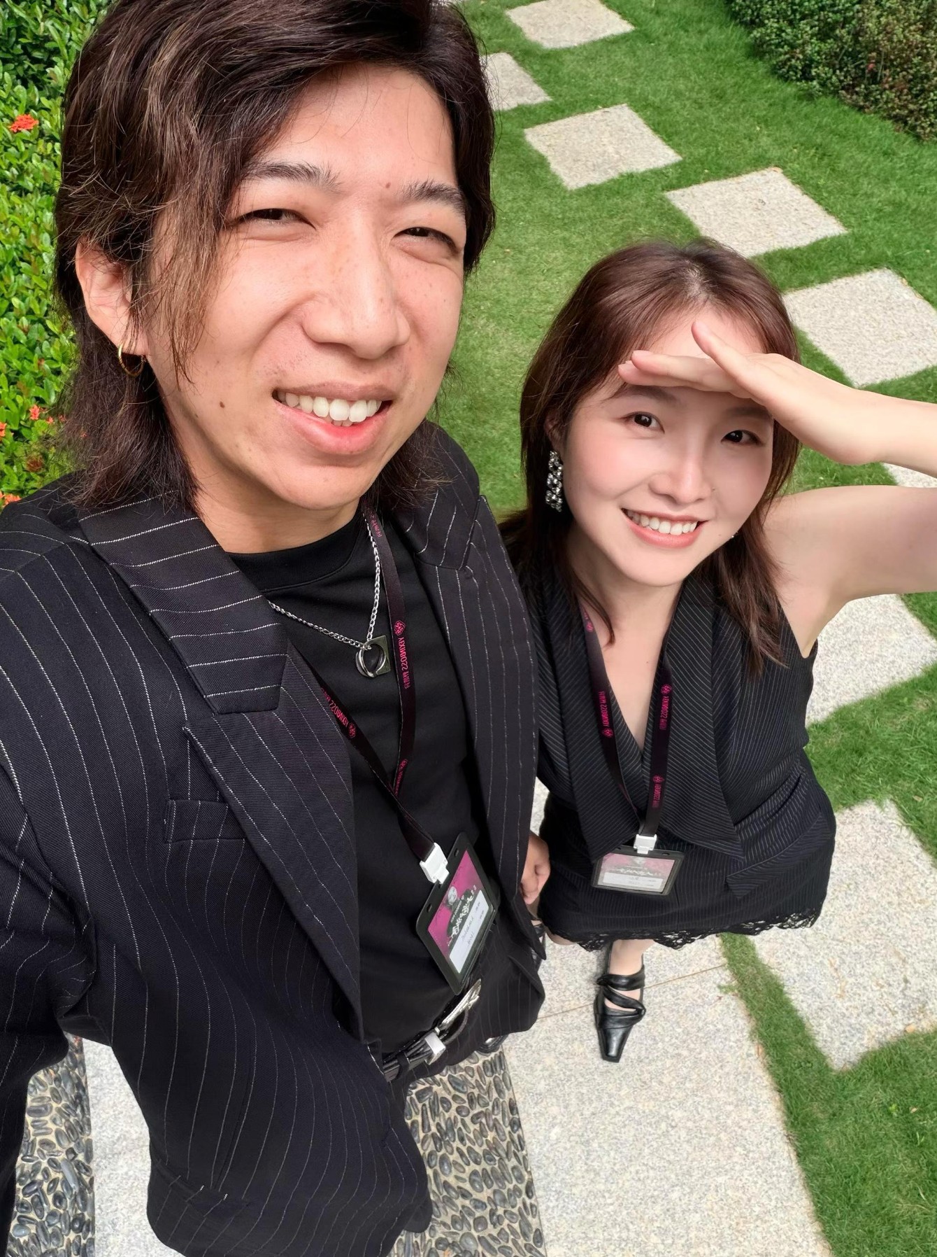 Hill Xue and Carey Dong smiling together outdoors on a garden path